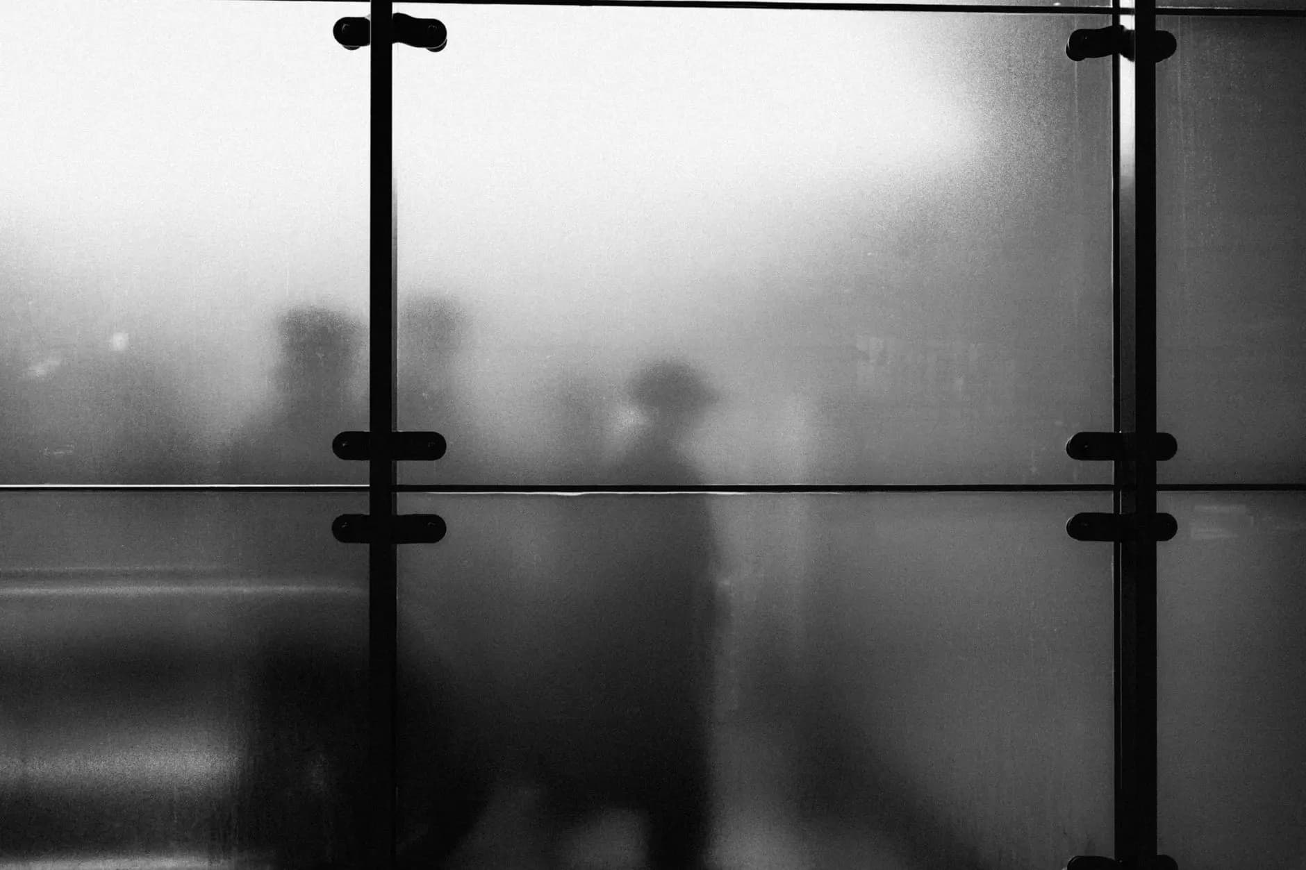 Artistic silhouettes on frosted glass create mystery in Amsterdam's urban environment.